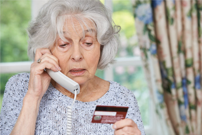 An elderly woman gives her credit card information over the phone grandparent scam