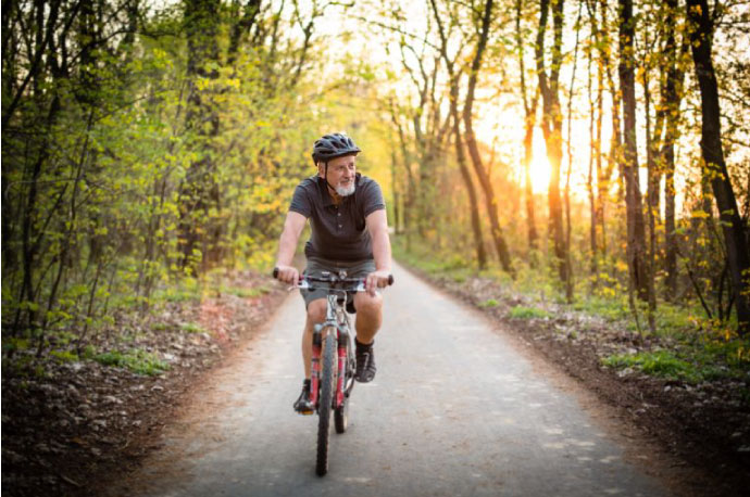 Elderly male riding his bike on paved path