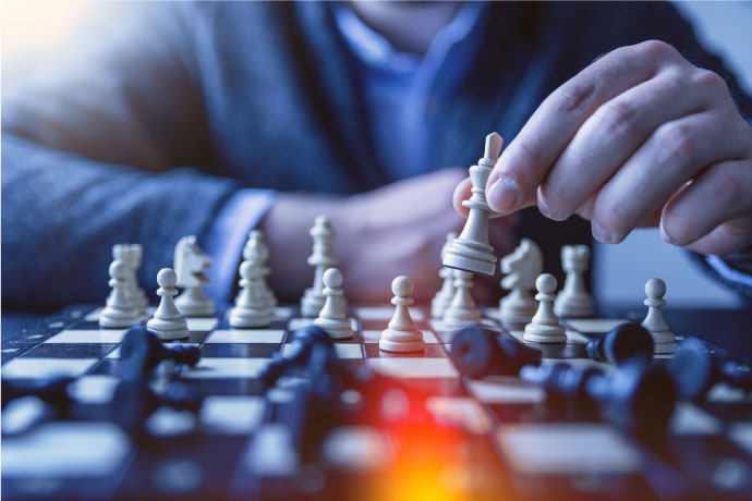 Person sitting down and playing chess and holding chess piece