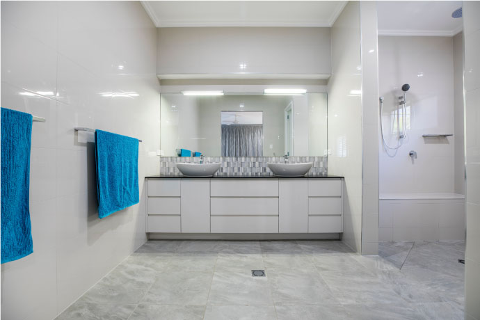 White bathroom with double vanity and open shower for bathroom safety