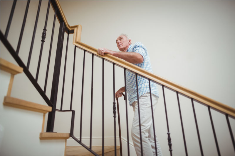 Elderly man walking upstairs with cane